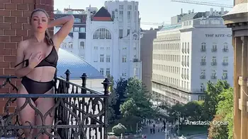 A woman undresses on a balcony in the city center. Public flashing.
